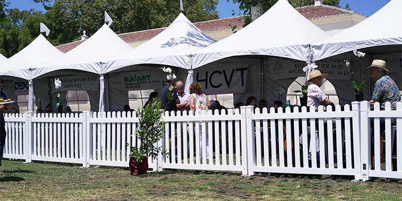 Clovis white vinyl picket portable fence panels in front of some covered seating at an outdoor event.