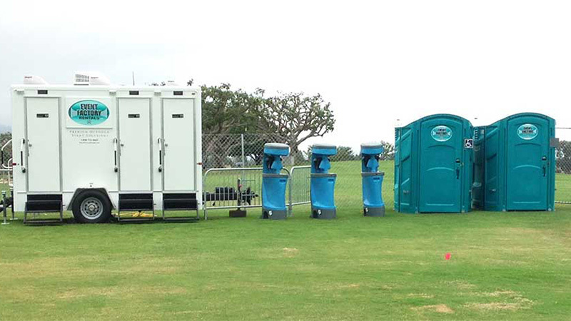 Canoga Park portable restroom rentals including a luxury restroom trailer, three hand wash stations and two handicap porta potties on a grass field.